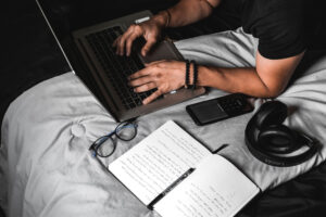 man writing SEO content on his computer while lying on his bed