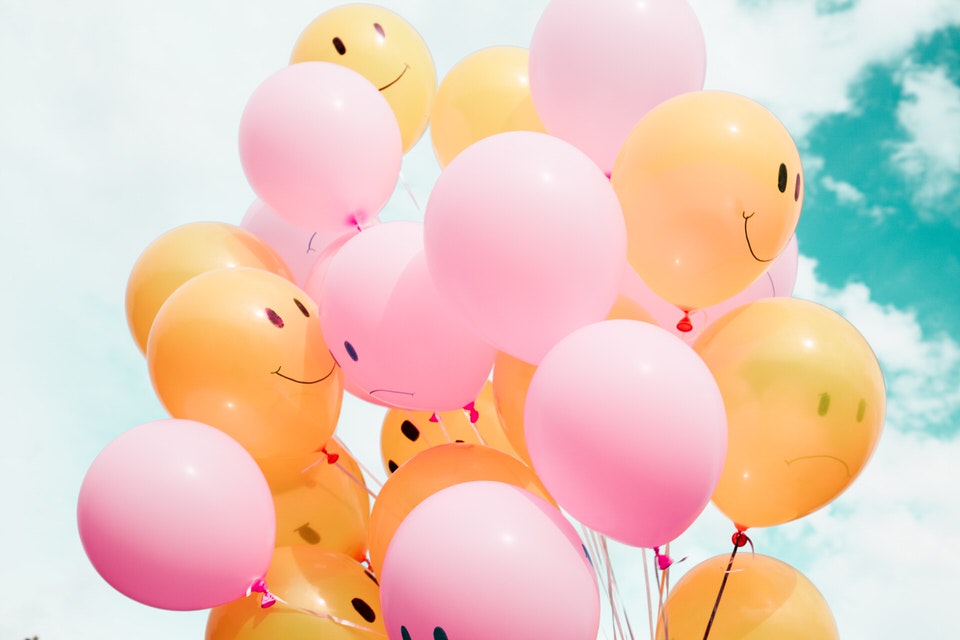 a bunch of orange and pink balloons with smiley faces on them